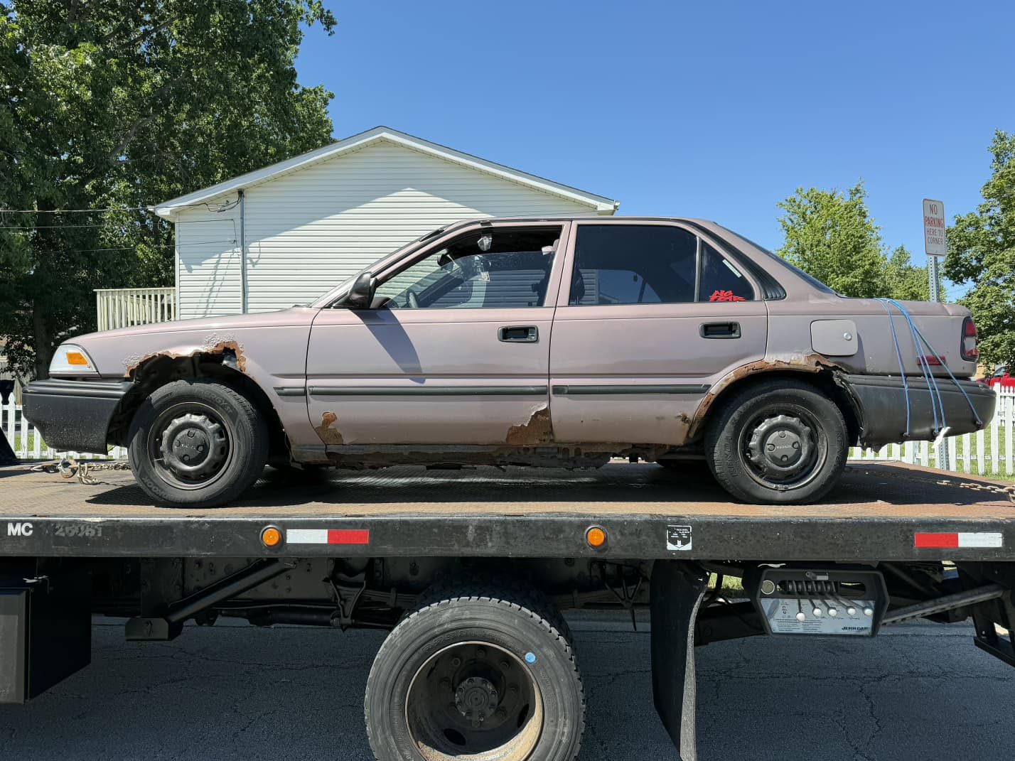 Rusty Toyota Corolla loaded on a flatbed for junk car removal